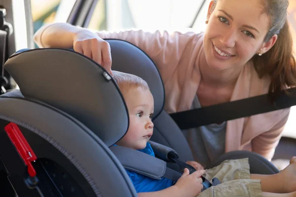 My childs safety is very important. Portrait of a mother fastening her baby boy safely in a car seat