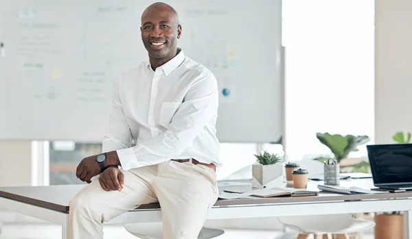 Black business man, leader and office in happy, proud and confident success for company goals in the corporate workplace. African guy in success at desk with smile in management and leadership work.