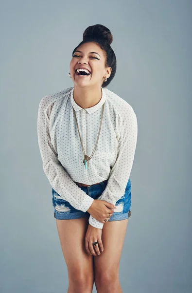Laughing hysterically. Studio shot of an attractive young woman laughing against a gray background
