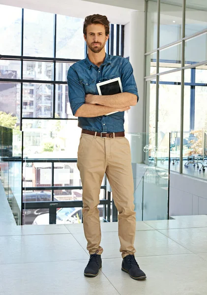 I carry my business around everywhere. Full length portrait of a handsome young businessman standing alone in a modern office and holding a tablet