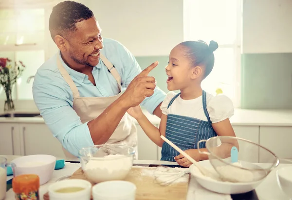 Baking dad, funny daughter and flour nose messy joke from happy learning, laughing child development and bonding in kitchen. Parent, kids and family home with cute, playful and sweet comedy together.