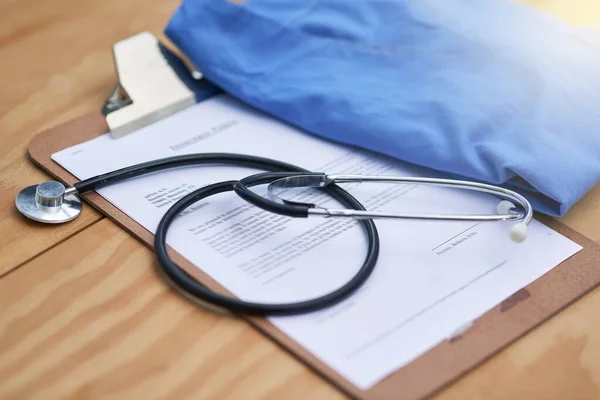 Diagnostic essentials. Closeup shot of a stethoscope lying on a doctors clipboard with a folded hospital gown