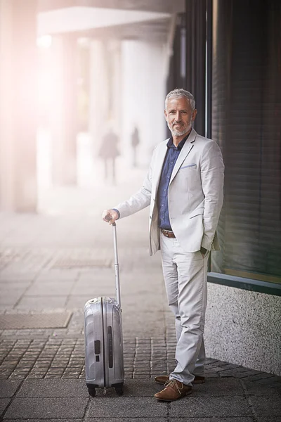 About to set off on a business trip. Portrait of a mature businessman standing with a suitcase outside