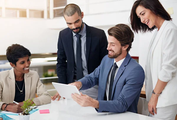 Collaborating to achieve success. businesspeople using a digital tablet in an office meeting