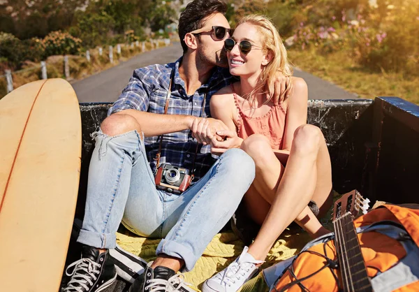 The greatest stories are formed on the open road. a young couple relaxing on the back of a pickup truck while on a road trip