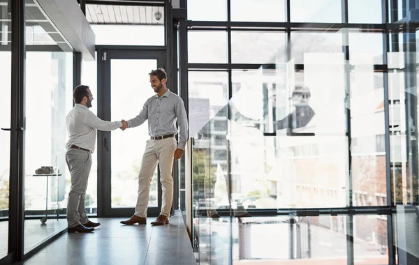 Forming partnerships to help better business. two businessmen shaking hands in an office