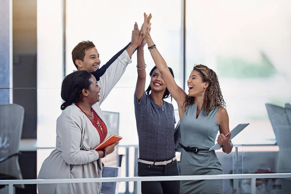 Teamwork makes the dream work. a group of colleagues high fiving together in an office