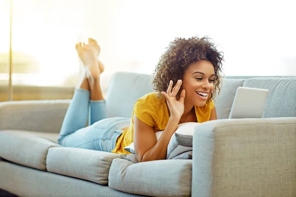 Hey, how are you. a young woman video chatting on her tablet at home