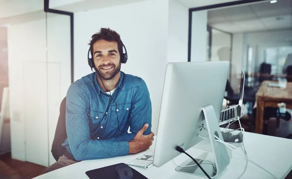 I am here to help you. High angle portrait of a handsome young businessman wearing a headset while sitting at his desk