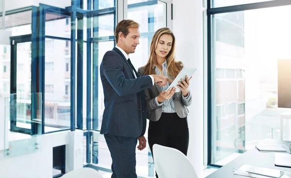 Collaborating on the biggest project yet. two businesspeople discussing something on a digital tablet