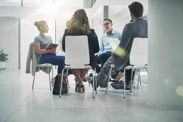 Planning is key to success. a group of coworkers talking together while sitting in a circle in an office