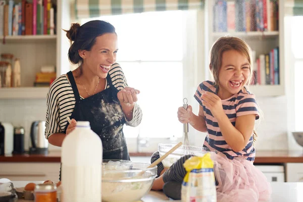 Flour and fun make for some delicious food. a little girl having fun baking with her mother in the kitchen