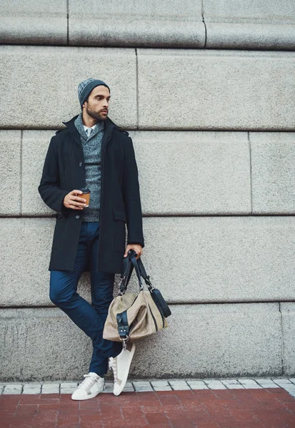 Urban fashion. a fashionable young man leaning against a building in an urban setting