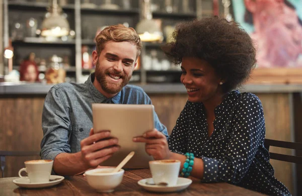 Sharing what they love. a young couple using a digital tablet together on a coffee date