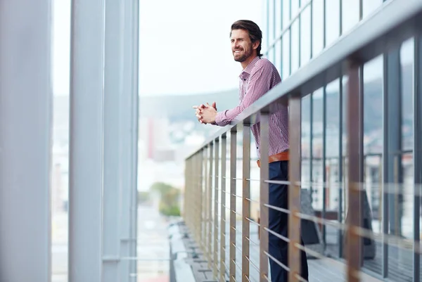 Taking a break on the balcony. a happy young businessman standing on the balcony of an office building
