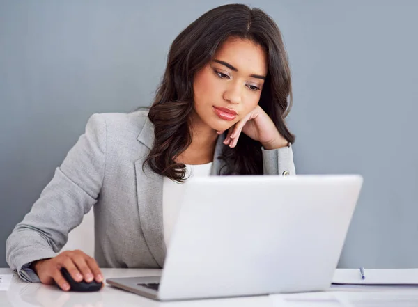 Feeling a little bored. a young businesswoman looking bored while working on her laptop