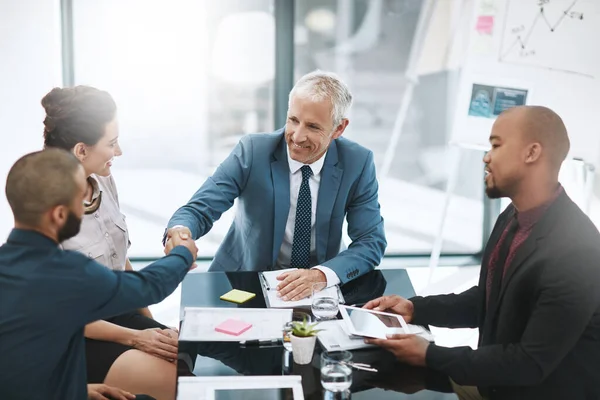 Welcome to the team. two businessmen shaking hands during a meeting in the boardroom