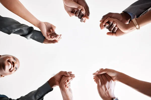 Diversity, support and collaboration of business people holding hands below in trust for company success. Team of corporate workers in a circle of success in a meeting together at a corporate company.