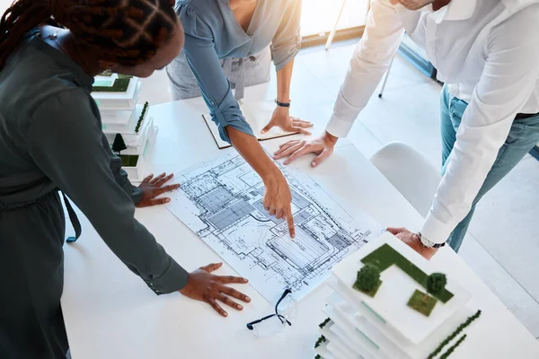 Architect, team and planning building blueprint in office for coworkers to look at before construction. Workers looking at designs and scale model for future architecture in corporate work setting