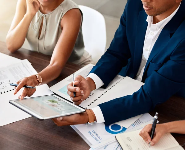 Business manager, ceo or leader holding digital tablet presenting financial data to colleagues in meeting. Brainstorming and planning ideas with market research in a finance startup company office.