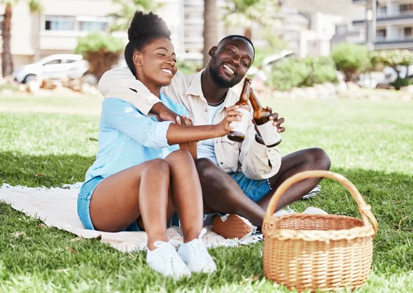 Couple on garden picnic date, black woman and drink bottle of beer together. Young african man, drinking alcohol and happy girl. Outdoor nature, park in city and love relationship time together.