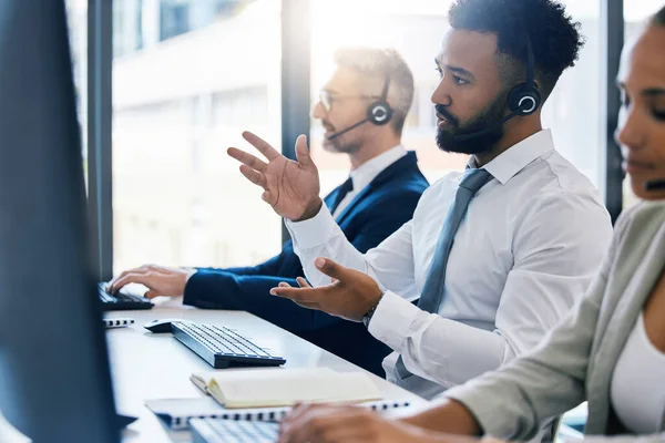 Call center, customer care and support with a man consultant in a headset working on a computer in his office. Contact us, crm and telemarketing with a male consulting on a call at his work desk.