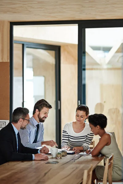 Strategy session in progress. a group of colleagues using a digital tablet together while working around a table in an office