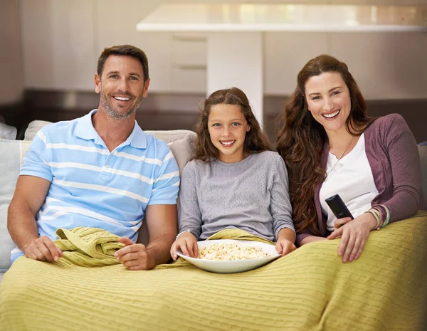 Family night with a film. a family sitting on their living room sofa watching a movie and eating popcorn