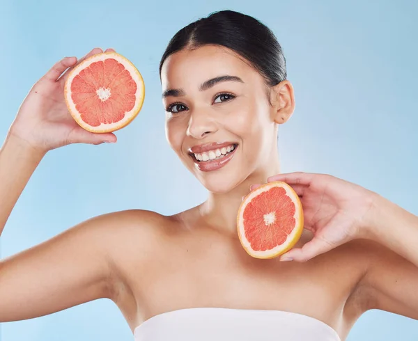 Grapefruit, skincare, face and diet wellness keeps her happy and healthy for skin healthcare, eat healthy fruit with nutrition. Portrait of a beauty woman in studio against a blue background.