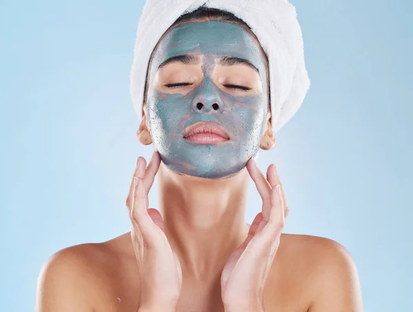 Skincare, beauty and face mask on a woman while doing her wellness routine in a studio. Latina girl with fresh, body care and hygiene lifestyle doing selfcare facial treatment to relax after a shower.