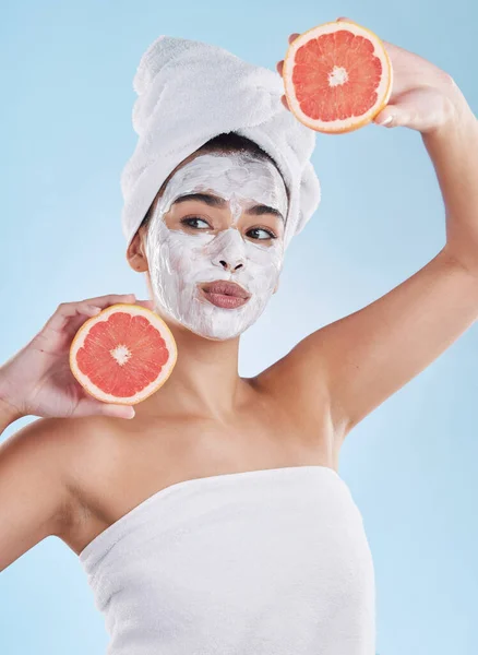 Skincare, health and face mask on a woman with a grapefruit doing an organic facial in studio. Girl with wellness, selfcare and healthy lifestyle doing a body care routine with tropical citrus fruit