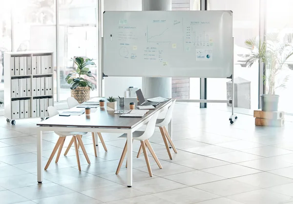 Boardroom, meeting or empty conference room with whiteboard, chairs and table interior of modern creative office space. Marketing data and charts for a business presentation, discussion of briefing.