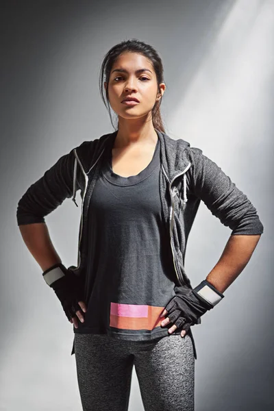 Motivated to reach her fitness goals. Portrait of a fit young woman in sports clothing posing against a gray background