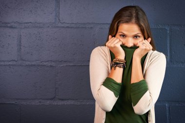 Whoopsie. a young woman covering her mouth against a brick wall background