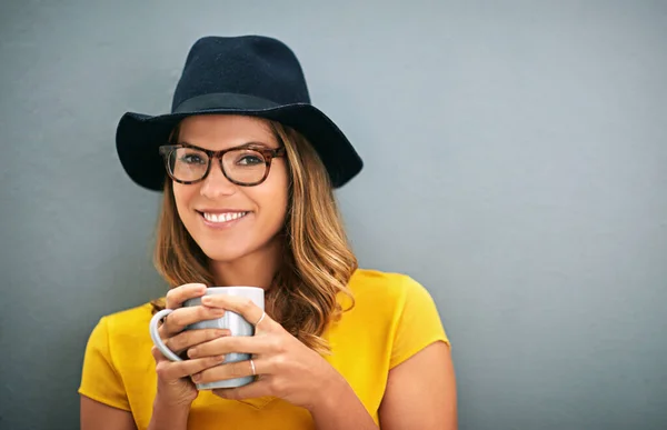 Great days start with great coffee. a young woman drinking coffee against a gray background