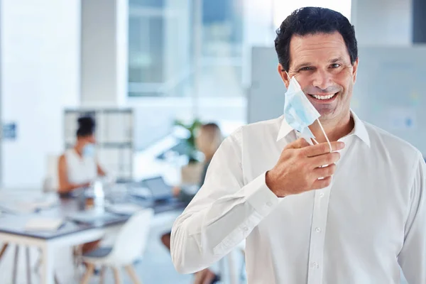 Covid, health and freedom, mask off for man in office after lockdown. Portrait of a happy businessman putting a face mask on to curb spread of virus in workplace and protect employees from infection