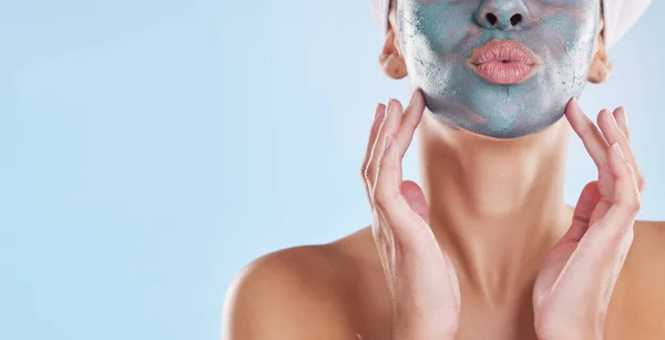 Facial, beauty and skincare with woman and face mask for clear skin, acne or luxury cosmetics against a blue background. Wellness, spa and relax with female and salon face treatment product.