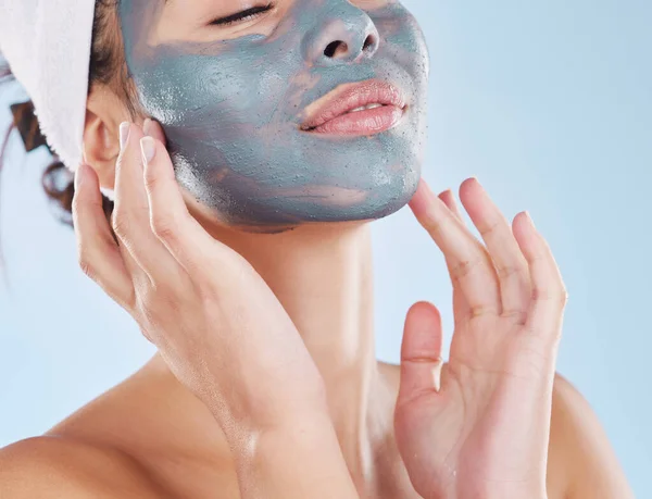 Skincare, facial and beauty with woman with face mask for cosmetics luxury, relax or acne against blue background studio. Salon, product and dermatology for wellness, spa and treatment.