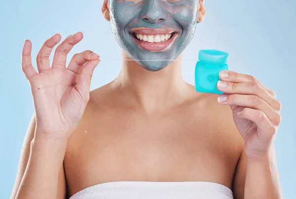 Teeth, skin and morning self care woman with flossing product, face mask and cleaning teeth for hygiene, wellness and body health. Model with bathroom skincare routine, blue studio background mockup.