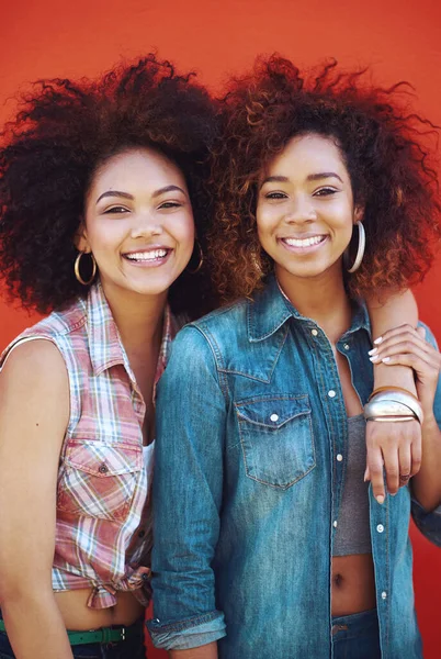 Best friends are like unbiological sisters. two young friends posing against a red background