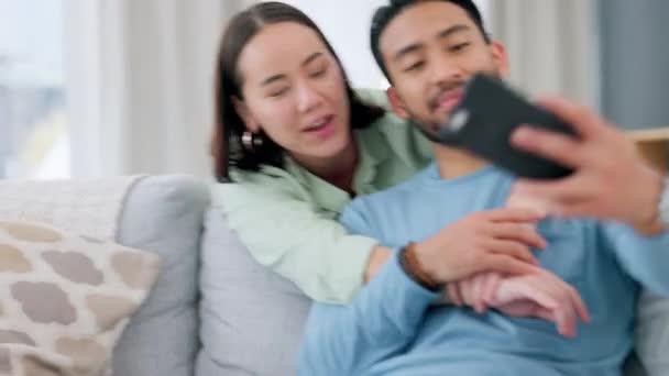 自宅の電話で自撮りをするアジアのカップル 自宅のリビングルームでのソーシャルメディアの投稿やカメラの笑顔のための愛とケア 男と女与える抱擁のための写真上のスマートフォン用インターネットアプリ — ストック動画