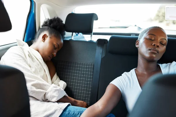 Lesbian couple sleeping in car or taxi after road trip, party and fun weekend as gay friends on vacation together. Tired African lgbt people, girls and women resting, relax and dreaming in back seat.