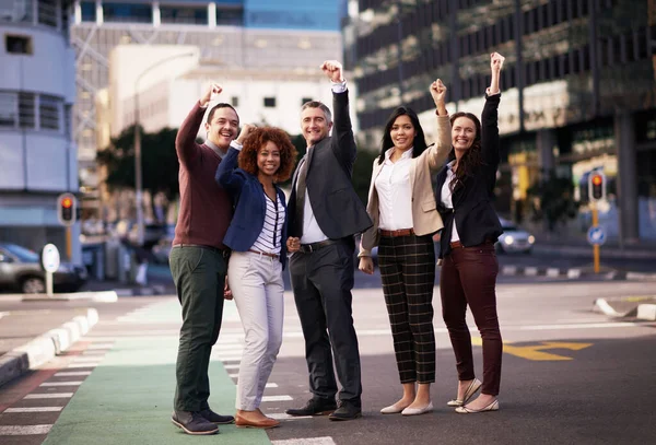 The best team in the City. a motivated business team putting their hands up for success while standing in the middle of a street