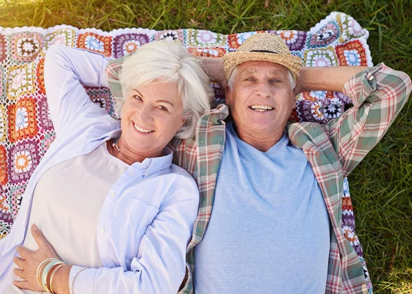 Its our time to relax. Portrait of a happy senior couple relaxing together on the lawn