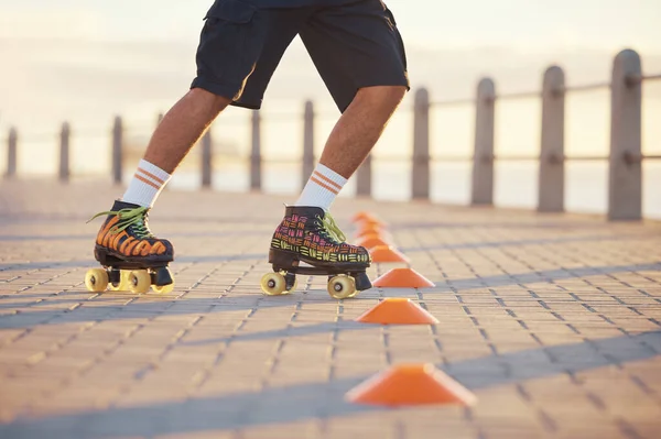 Roller skates, sport and feet with a man riding around cones for training, fitness and exercise on the promenade by the beach. Male athlete roller skating outside for sports, health and recreation.