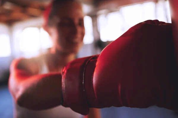 Boxing, fitness and sport with strong woman, boxing gloves to hit, punch and fight during training at a gym. Fit and athletic boxer female doing a workout during self defense exercise class.