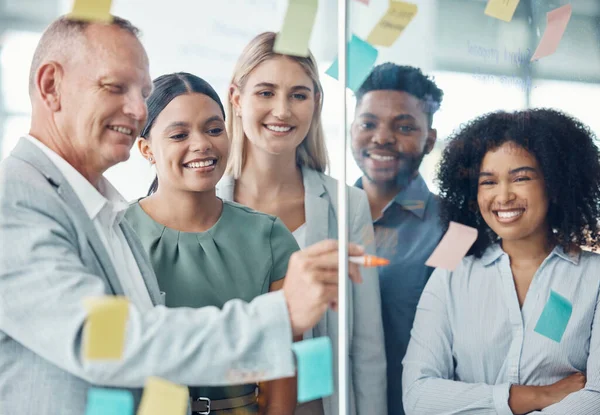 Team, strategy and business people writing on sticky notes in a meeting about the vision, mission and goals of the company. Teamwork, smile and happy group of employees brainstorming in modern office.