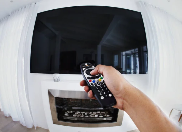 Get ready to be entertained. POV shot of a person aiming a remote control at a flat screen television