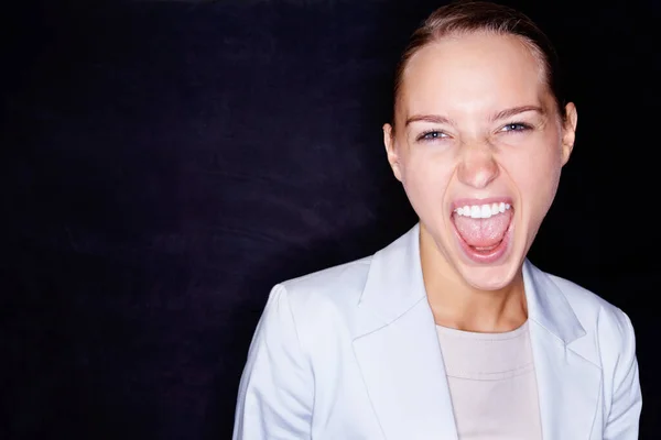 Aggressive business woman screaming on black background. Young business woman screaming in anger , isolated against black background