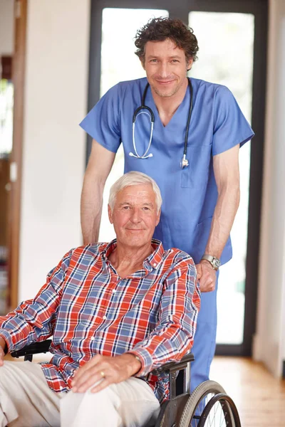 他是个很好的照顾者 男医生和坐在轮椅上的老年病人站在一起的画像 — 图库照片